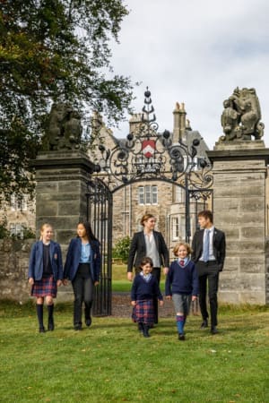 Pupils of various ages walk out of the gates on the green lawn at St Leonards School.